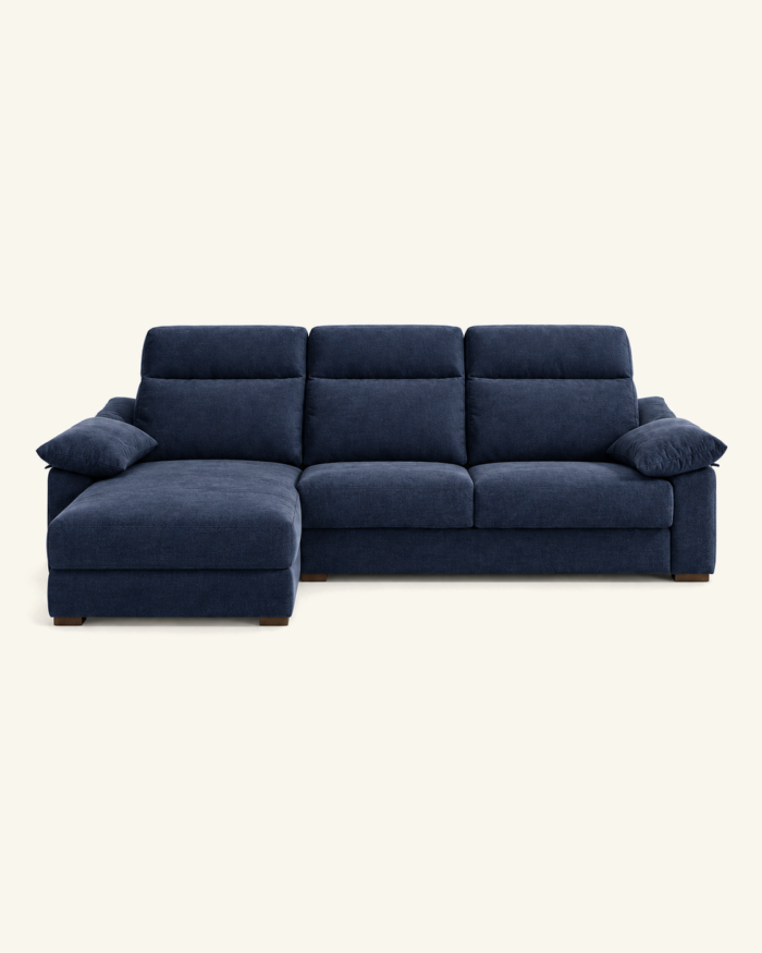 Sofá cama Nara con chaise longue Sofá cama Nara azul marino con chaise longue a la izquierda, brazos acolchados y patas bajas de madera sobre fondo beige.
