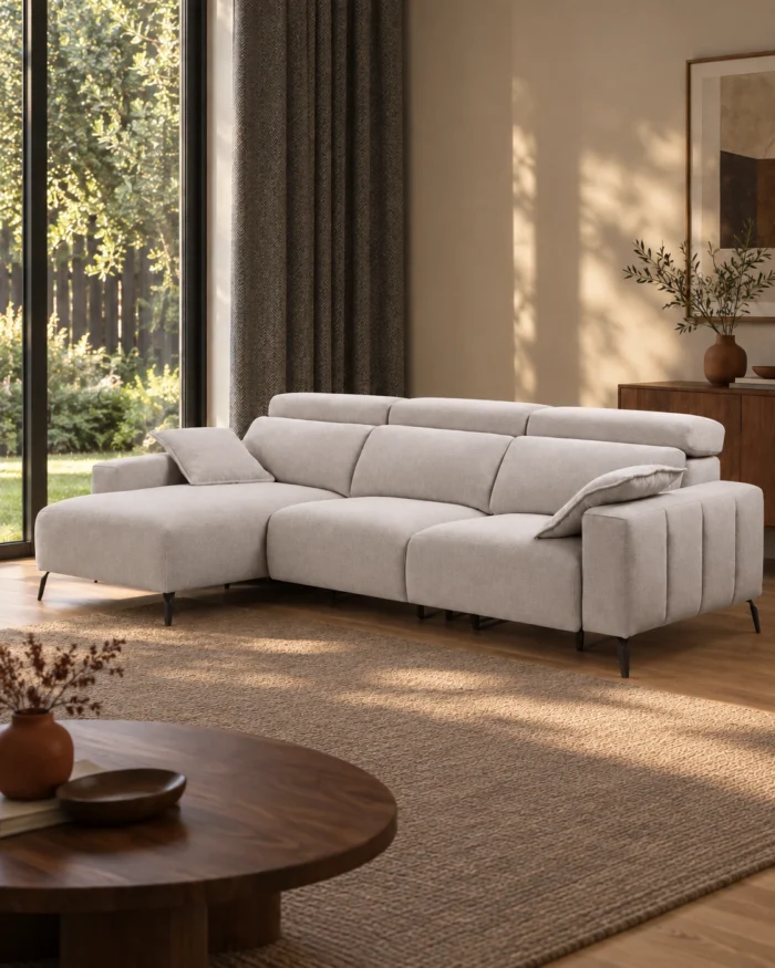 Sofá Valeria beige con chaise longue a la izquierda en un salón con ventanal, madera oscura y detalles terracota