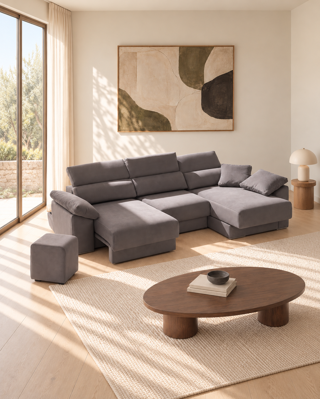 Sofá Alquézar gris con asientos extendidos, cabezales elevados y puf en salón contemporáneo.